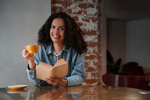 Donna del colpo medio con il libro in caffetteria