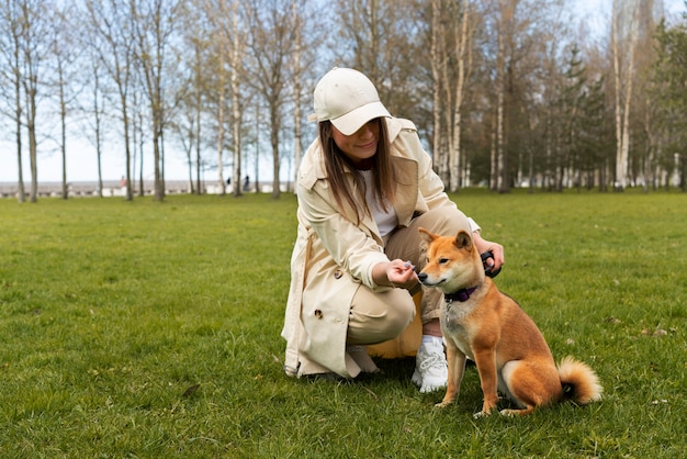 Donna del colpo pieno che alimenta il cane sveglio di shiba inu