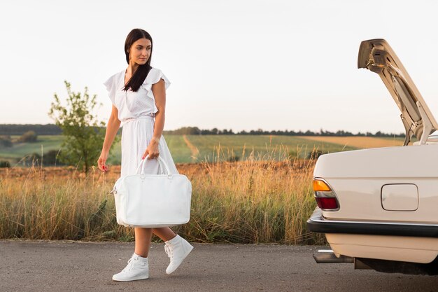 Donna del colpo pieno che cammina con la borsa