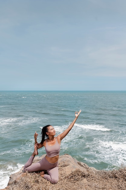 Donna del colpo pieno che fa yoga all'aperto