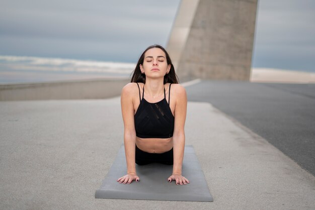 Donna del colpo pieno che fa yoga sulla stuoia