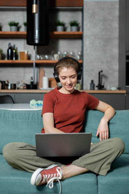 Donna del colpo pieno che lavora al computer portatile a casa