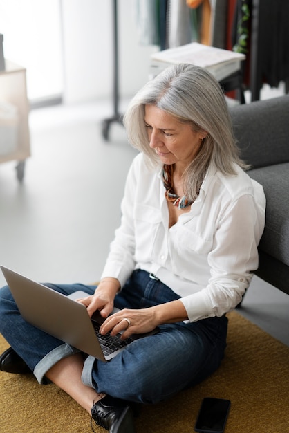 Donna del colpo pieno che lavora al computer portatile a casa