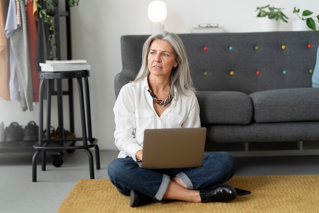 Donna del colpo pieno che lavora al computer portatile all'interno