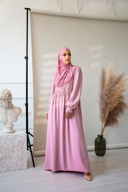 Donna del colpo pieno che posa con l'hijab rosa