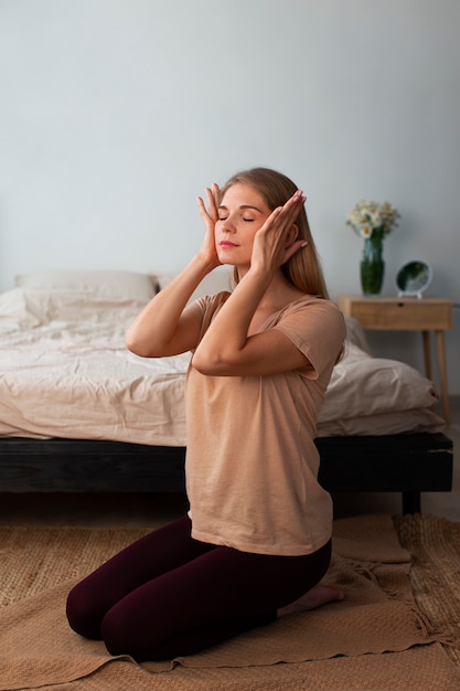 Donna del colpo pieno che pratica yoga facciale