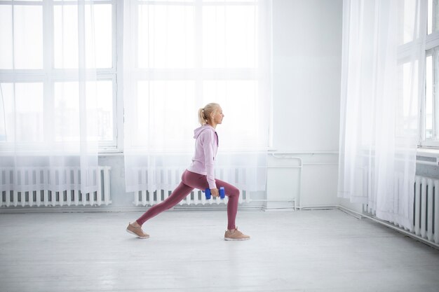 Donna del colpo pieno che si esercita con i dumbbells