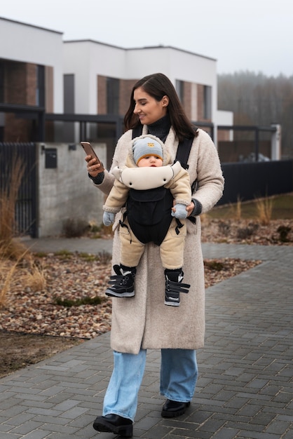 Donna del colpo pieno che tiene bambino in marsupio