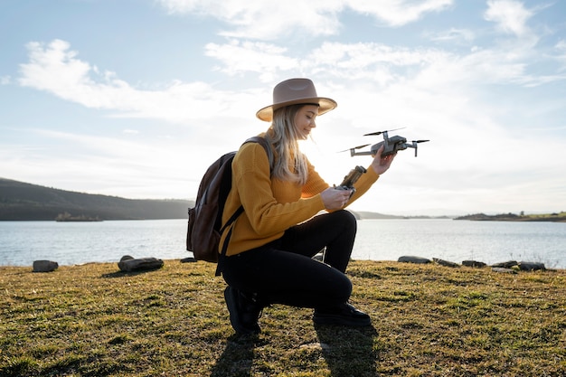 Donna del colpo pieno che tiene drone all'aperto