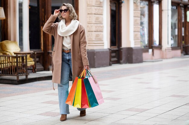 Donna del colpo pieno che trasporta le borse della spesa