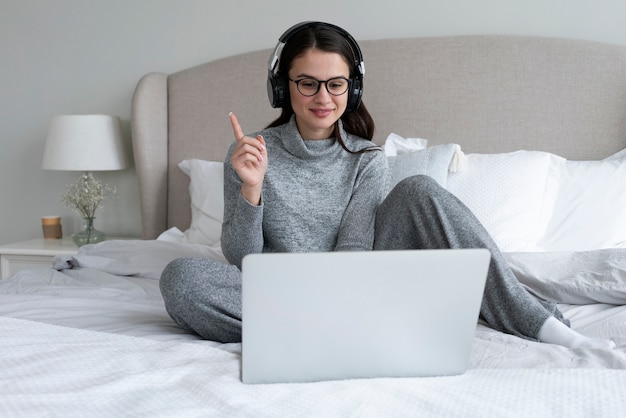 Donna del colpo pieno con il computer portatile in camera da letto