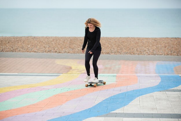 Donna del colpo pieno su skateboard all'esterno