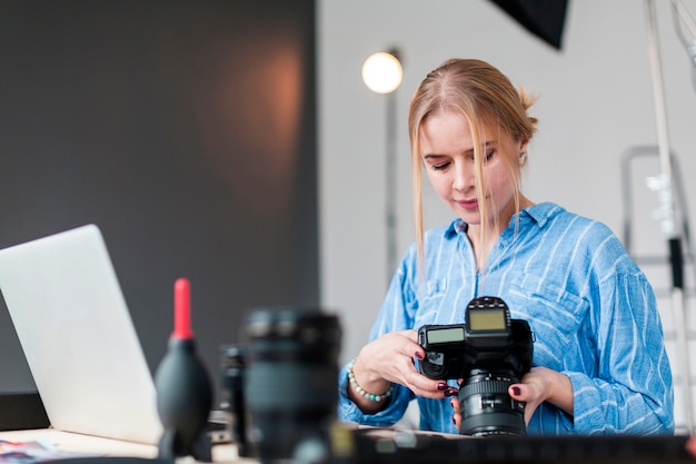 Donna del fotografo e la sua lente che stanno al suo scrittorio