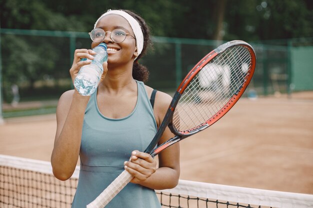 Donna del giocatore di tennis che beve acqua da un'acqua