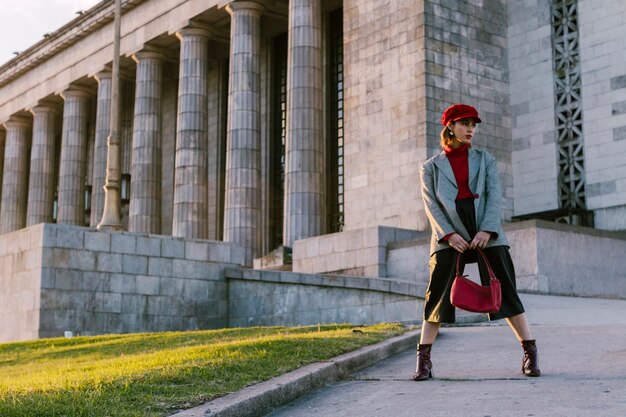 Donna del modello di moda di bellezza che indossa la borsa alla moda della tenuta del cappotto a disposizione