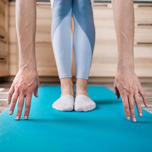 Donna del primo piano che allunga sulla stuoia di yoga