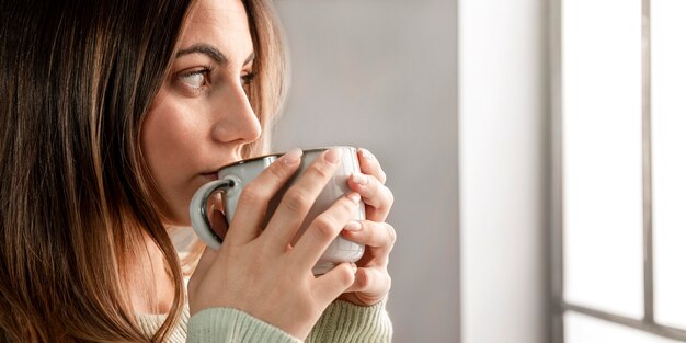 Donna del primo piano che beve dalla tazza