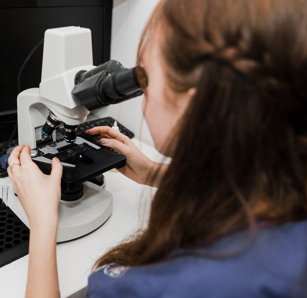 Donna del primo piano che osserva tramite il microscopio