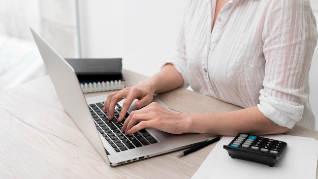 Donna del primo piano che scrive sul computer portatile