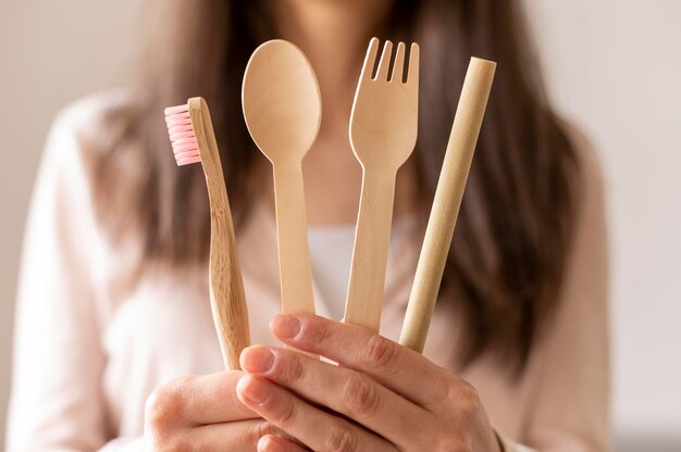 Donna del primo piano che tiene coltelleria di legno