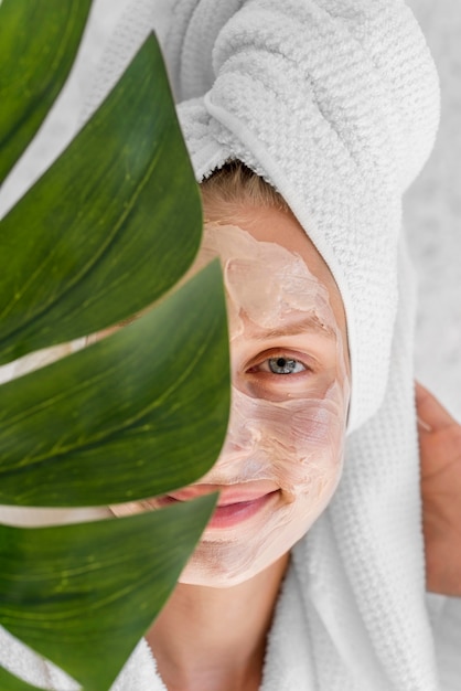 Donna del primo piano che tiene foglia di monstera