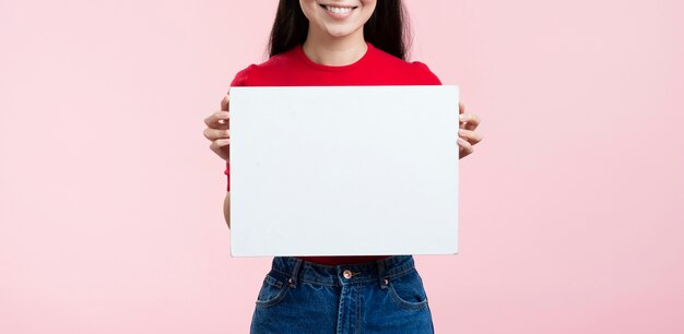 Donna del primo piano che tiene foglio di carta bianco