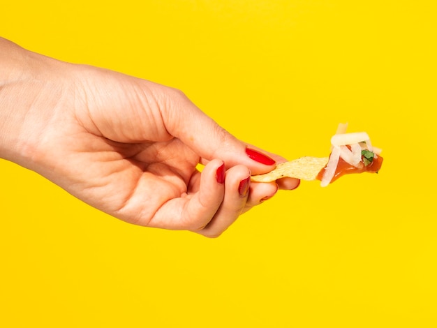 Donna del primo piano che tiene i chip di tortiglia con fondo giallo