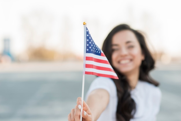 Donna del primo piano che tiene sorridere della bandiera degli SUA