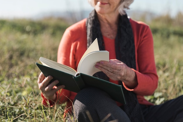 Donna del primo piano con il libro all'aperto