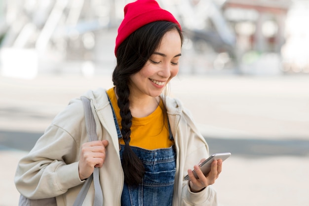 Donna del ritratto con lo zaino che controlla cellulare