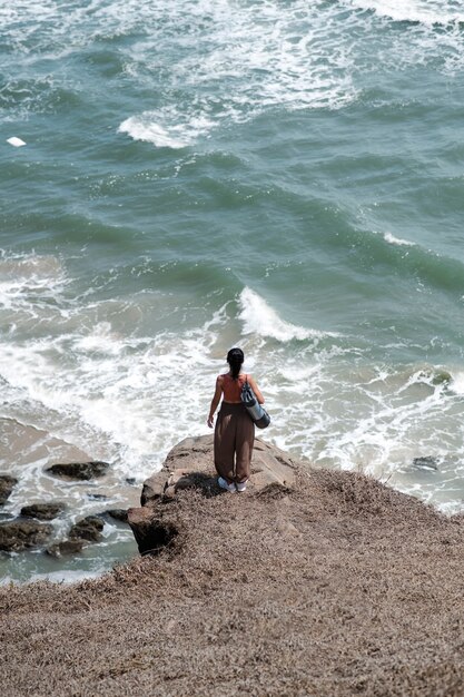 Donna del tiro lungo al mare con la stuoia di yoga