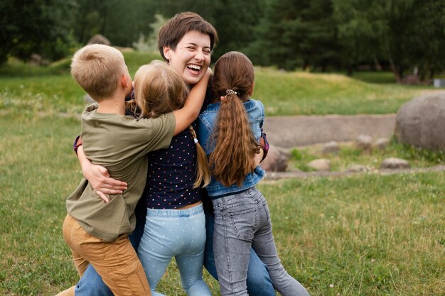 Donna del tiro medio che abbraccia i bambini