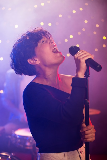 Donna del tiro medio che canta sul palco