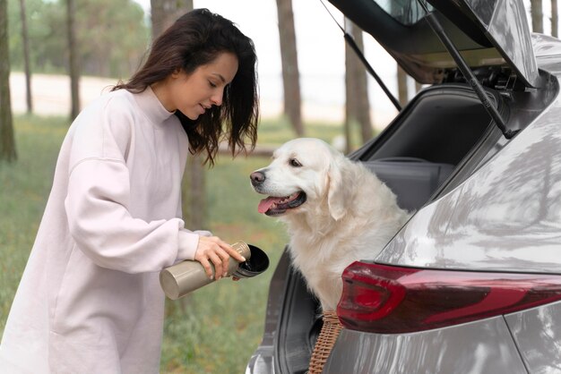 Donna del tiro medio che dà acqua al cane