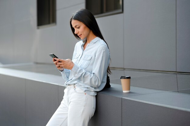 Donna del tiro medio che digita sullo smartphone