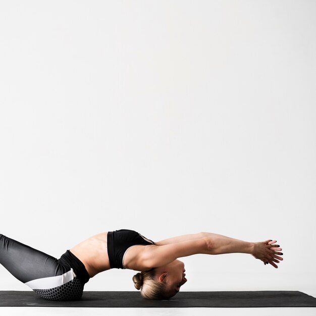 Donna del tiro medio sulla stuoia di yoga