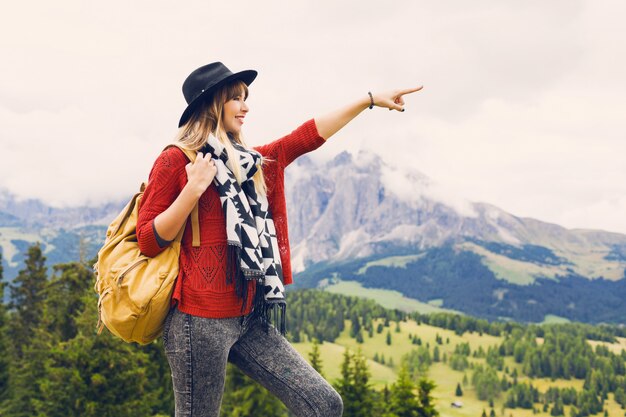 Donna del viaggiatore con cappello e zaino che gode della vista incredibile sulle montagne