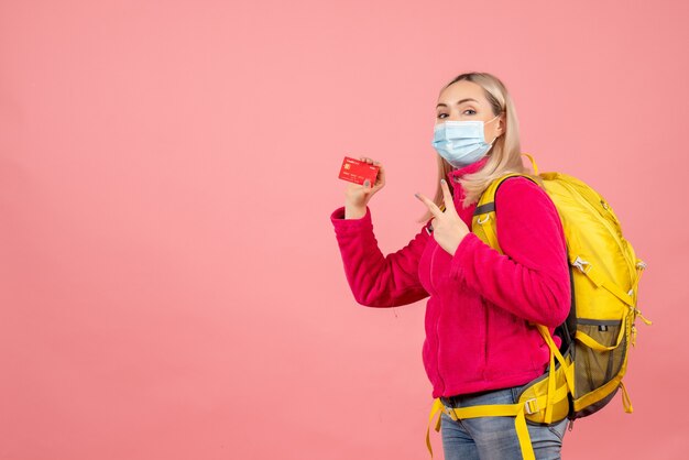 Donna del viaggiatore di vista frontale con la carta della tenuta della maschera che fa segno di vittoria