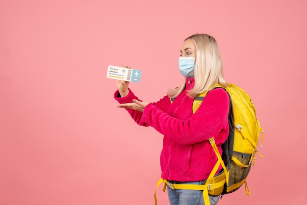 Donna del viaggiatore di vista frontale con lo zaino giallo che indossa il biglietto della tenuta della maschera