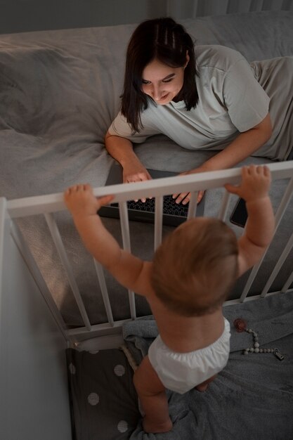 Donna dell'angolo alto con il bambino che lavora al computer portatile