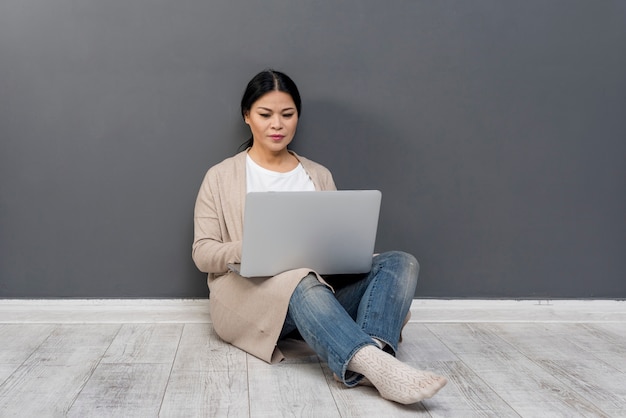 Donna dell'angolo alto sul pavimento con il computer portatile