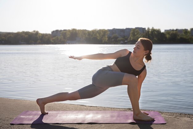 Donna della foto a figura intera che allunga sulla stuoia di yoga