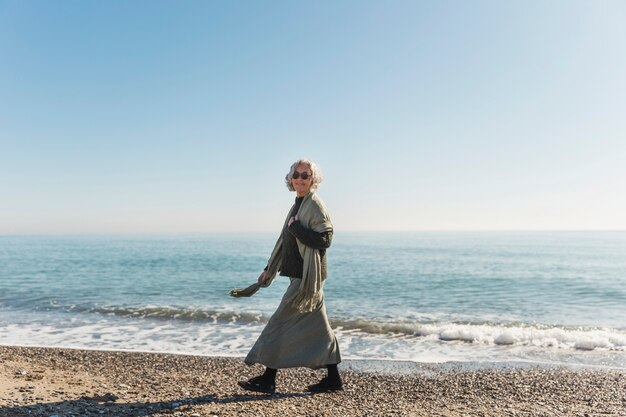 Donna della foto a figura intera che cammina sulla spiaggia