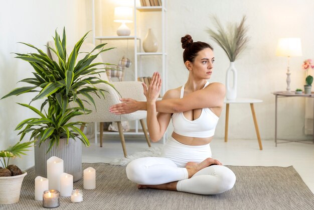 Donna della foto a figura intera che fa yoga all'interno