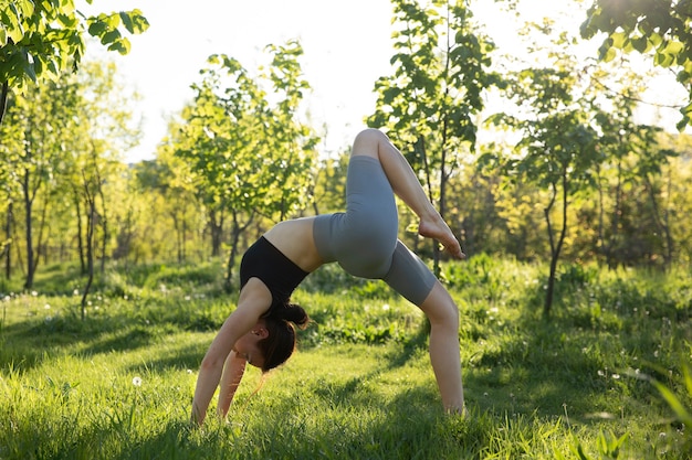 Donna della foto a figura intera che fa yoga in natura