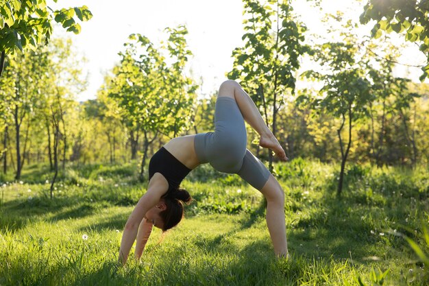 Donna della foto a figura intera che fa yoga in natura