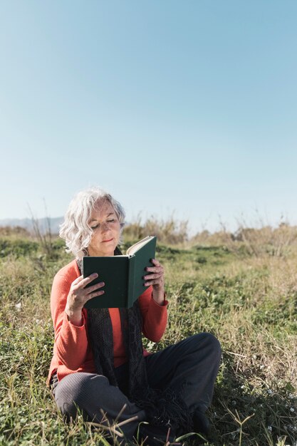 Donna della foto a figura intera che legge all'aperto