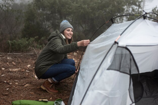 Donna della foto a figura intera che mette su una tenda