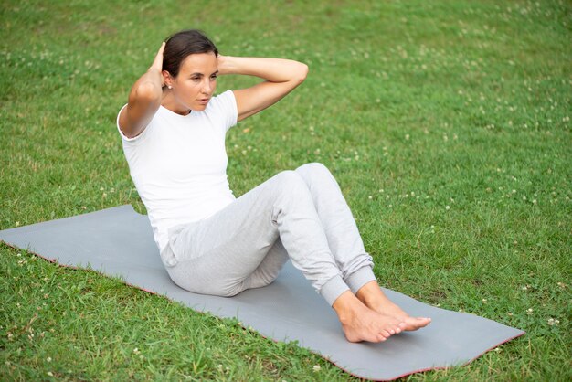 Donna della foto a figura intera che si esercita sulla stuoia di yoga