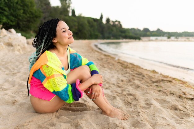 Donna della foto a figura intera che si siede sulla spiaggia